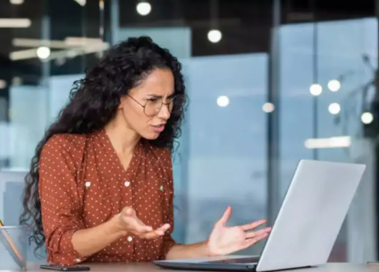 Frustrated job seeker looking at laptop in office